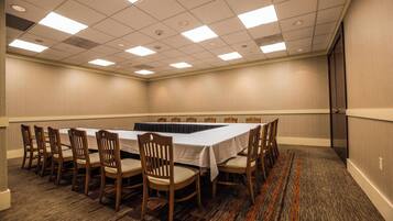 A conference room with a long table, chairs, carpeted floor, and a door on the right.