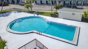 A rectangular swimming pool with a curved edge, surrounded by a concrete deck and a metal railing. - Stayable St. Augustine (St. Augustine)
