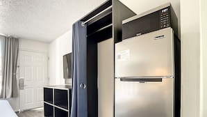 A compact kitchen with a stainless steel refrigerator, a built-in oven, and a microwave. There is a small seating area with a table and chairs. - Stayable St. Augustine (St. Augustine)