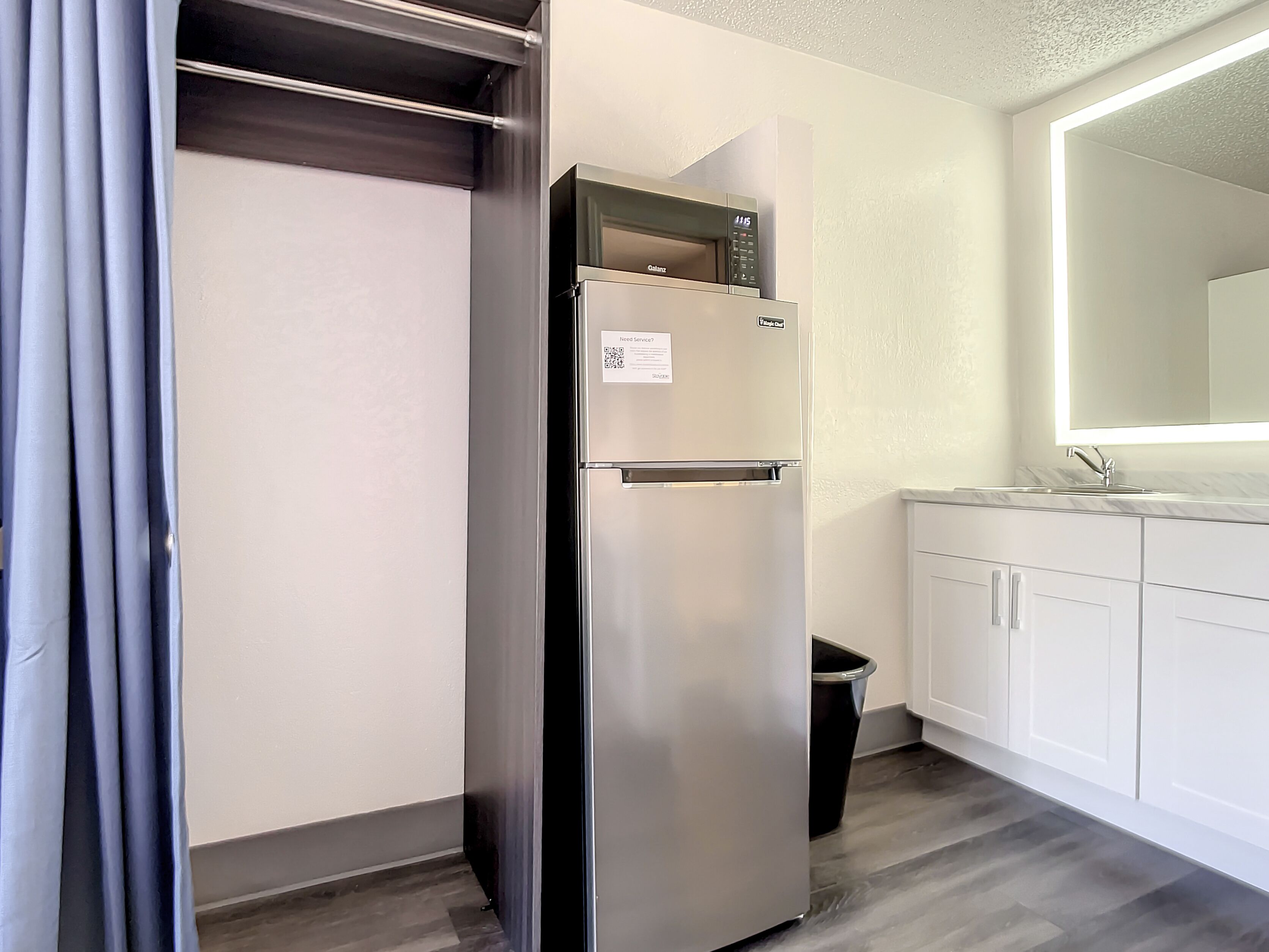 A modern kitchen with a stainless steel refrigerator, white cabinets, and a built-in microwave.