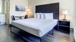A modern hotel room with a large bed, a desk, and two bedside lamps. - Stayable St. Augustine (St. Augustine)