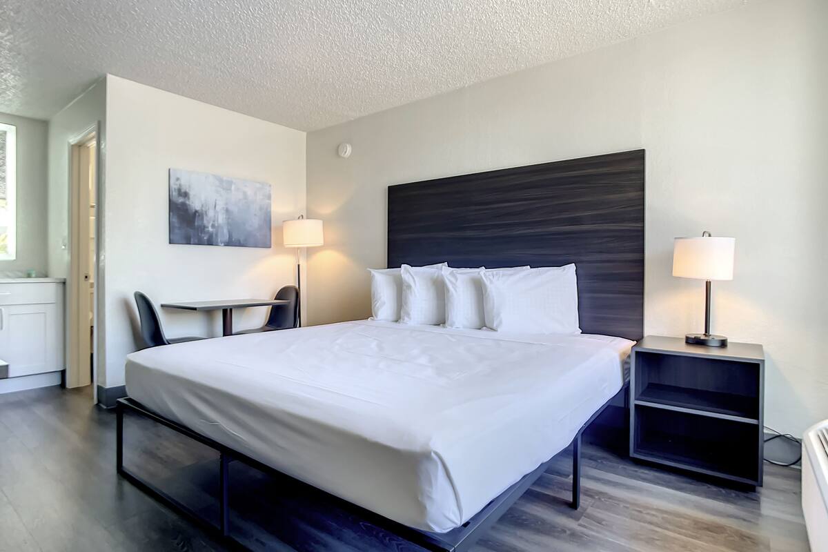 A modern hotel room with a large bed, a desk, and two bedside lamps.
