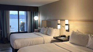 A hotel room with two beds, a nightstand, a lamp, and a view of the water. - Wyndham Garden Lake Guntersville (Guntersville)