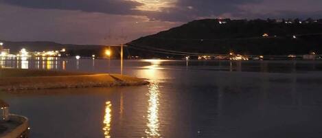 A nighttime waterfront scene with a dock and calm water reflecting lights.