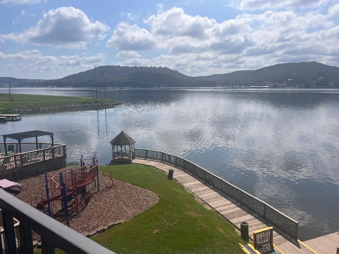 A lakeside view with a wooden dock, a playground, and a gazebo.