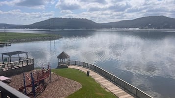 A lakeside view with a wooden dock, a playground, and a gazebo.