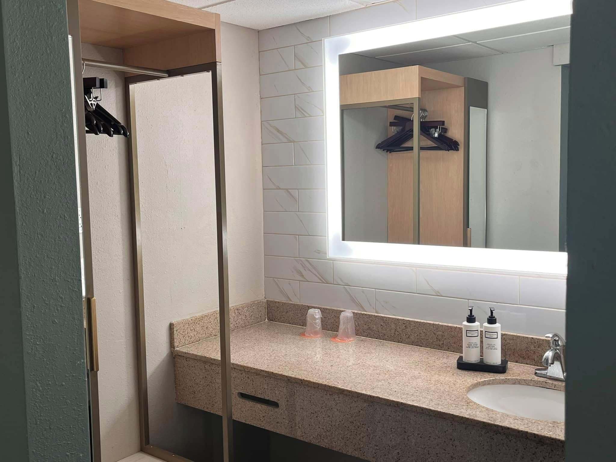 A modern bathroom with a shower, a vanity with a mirror, and toiletries.