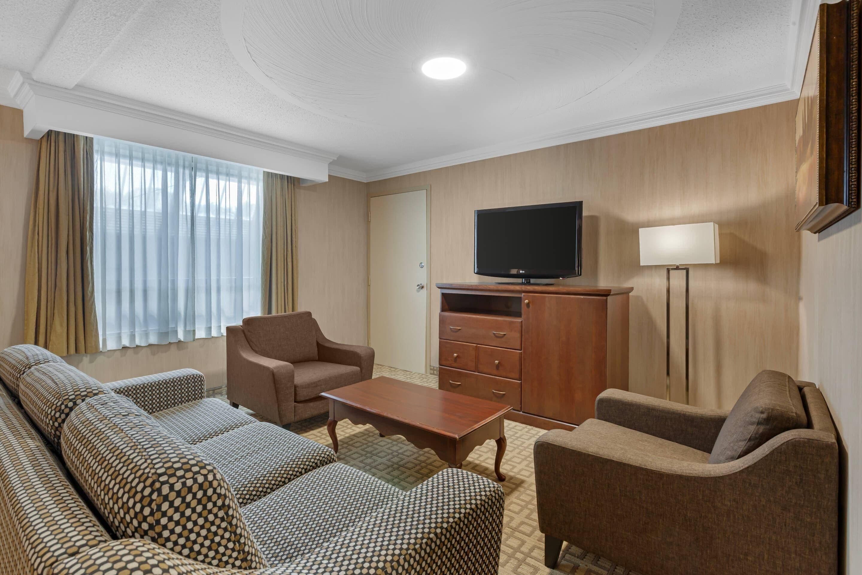 Une chambre d’hôtel comprenant un canapé, un téléviseur, une armoire et une lampe.