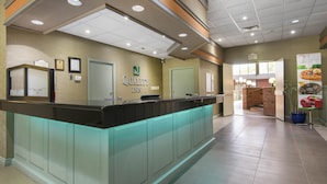 A reception area with a glass counter, a sign for Quality Inn, and a view of the restaurant area. - Quality Inn & Conference Centre (Midland)