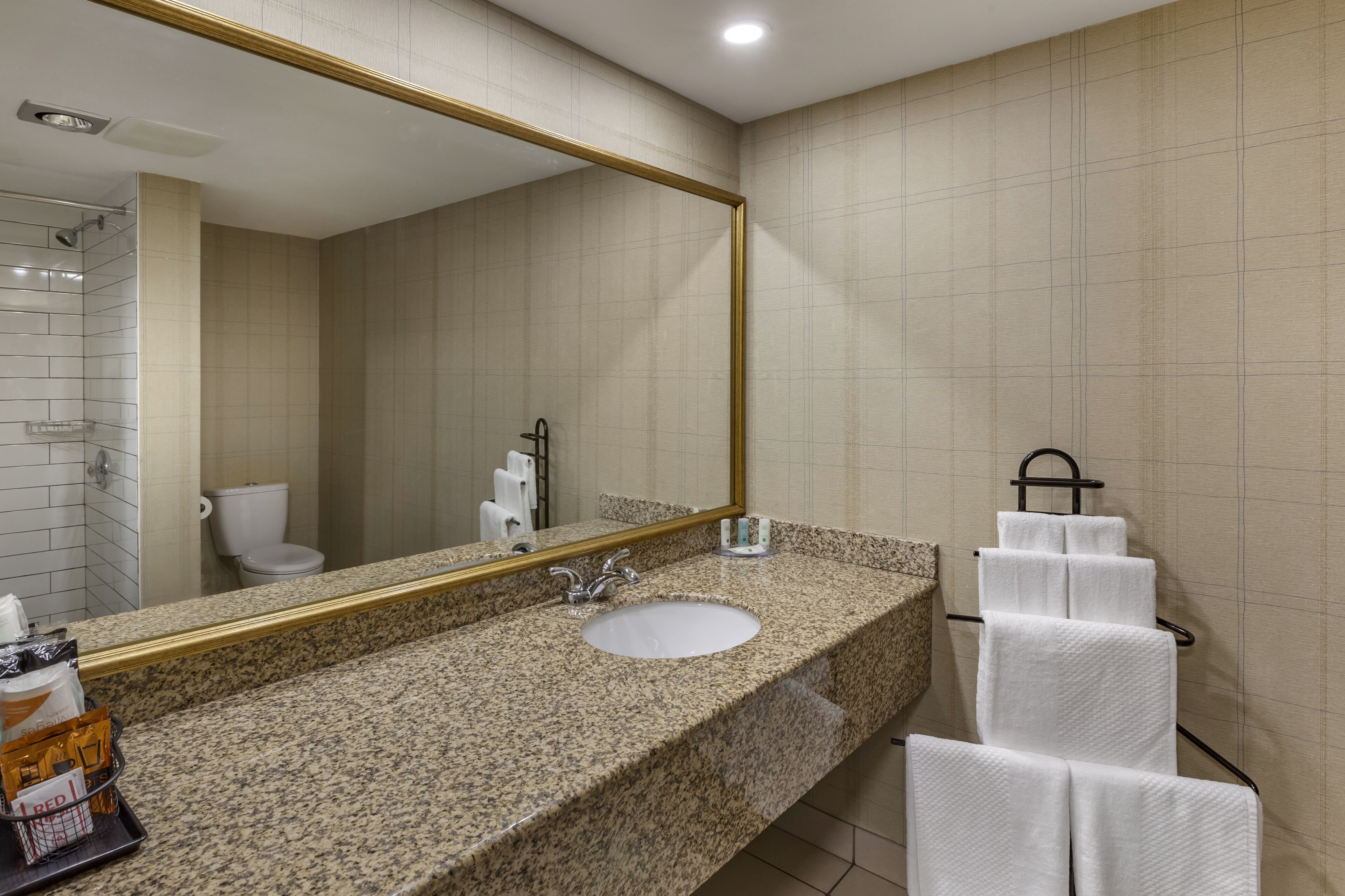 A bathroom with a granite countertop, a sink, a mirror, and a towel rack.