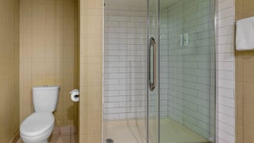 Een badkamer met toilet, een douchecabine van glas en betegelde wanden.