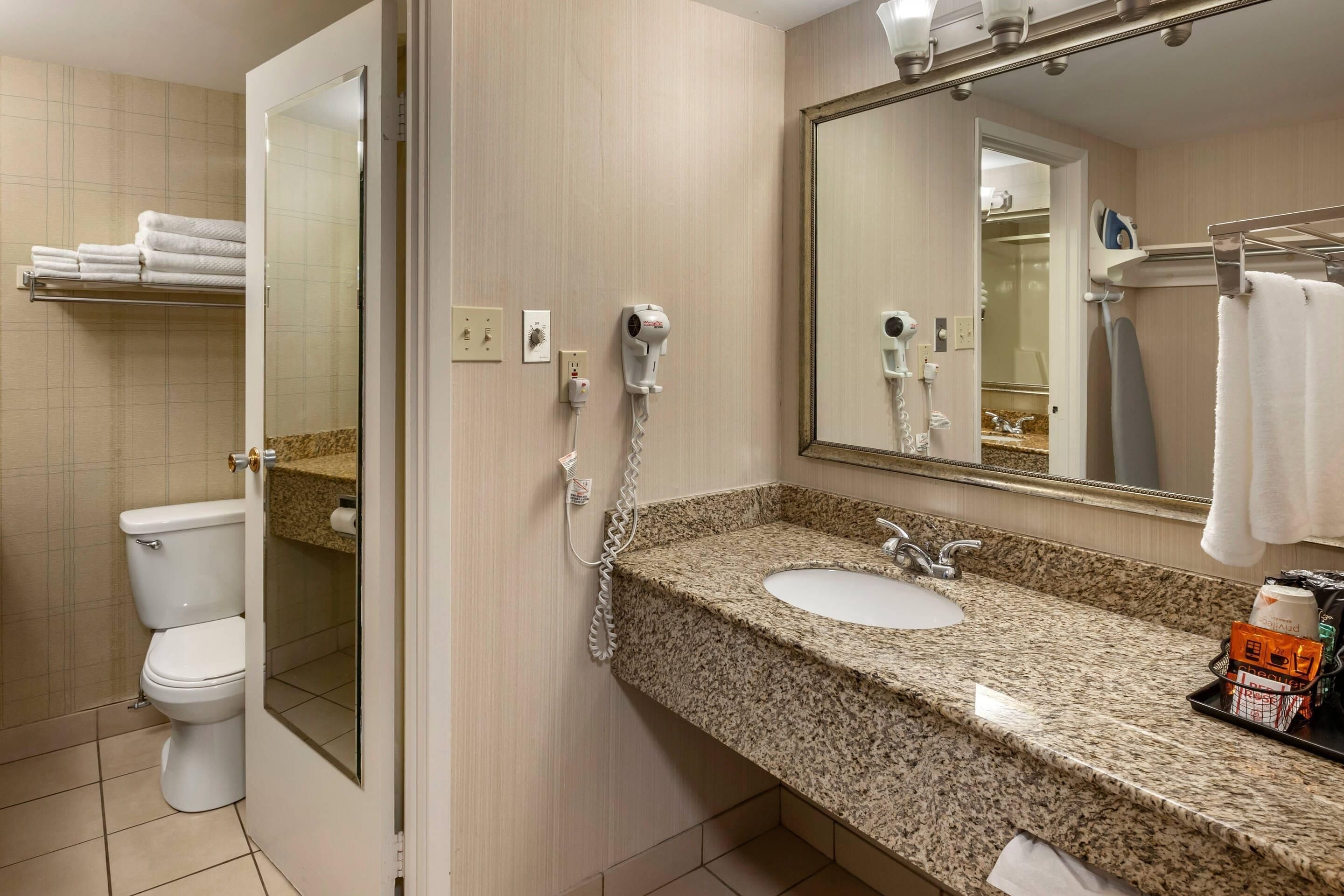 Une salle de bain équipée de toilettes, d’un lavabo et d’un sèche-cheveux.