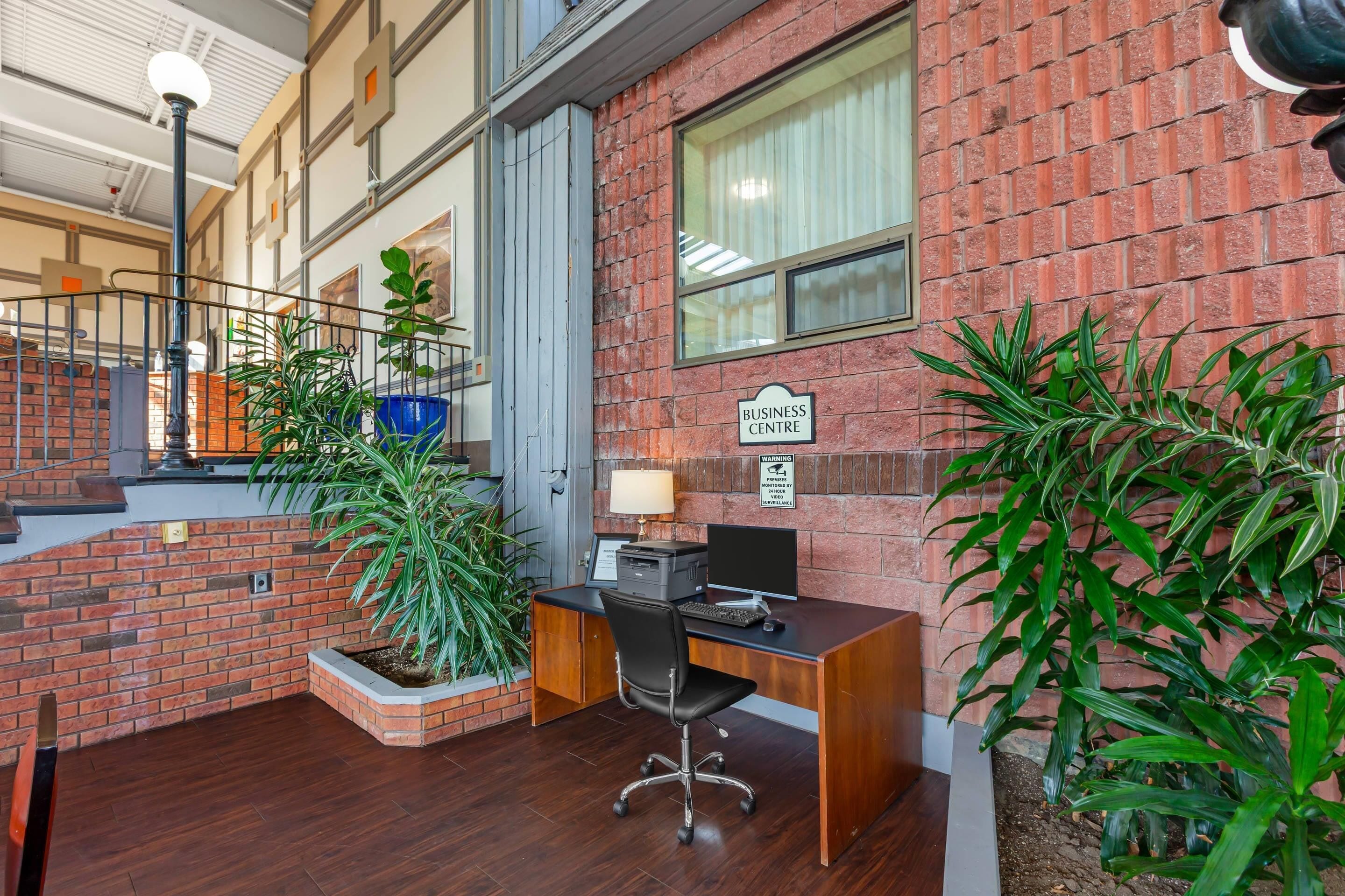 A business center with a desk, computer, and a sign indicating surveillance.