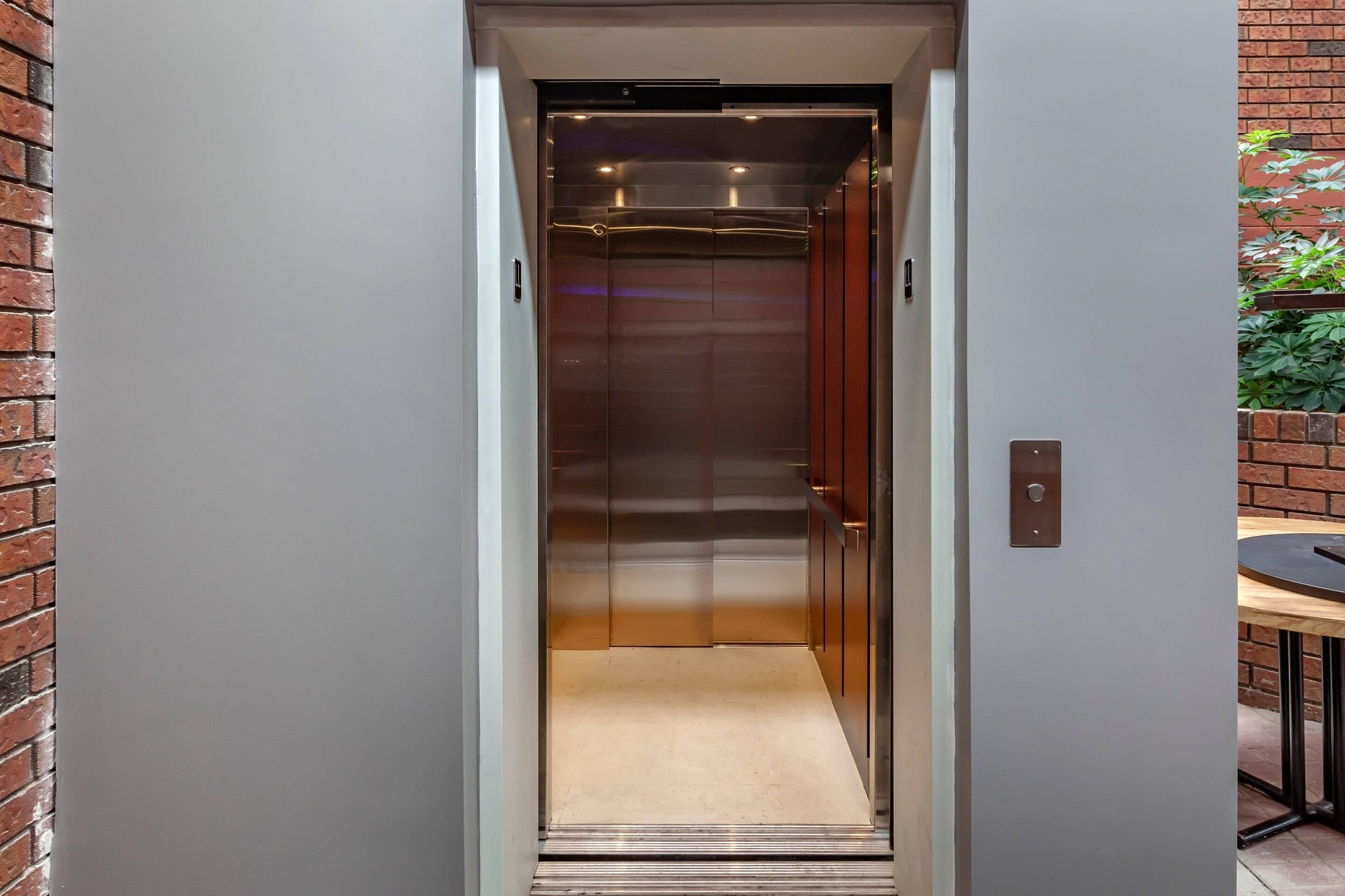 Un ascensor con interior metálico y piso alfombrado.
