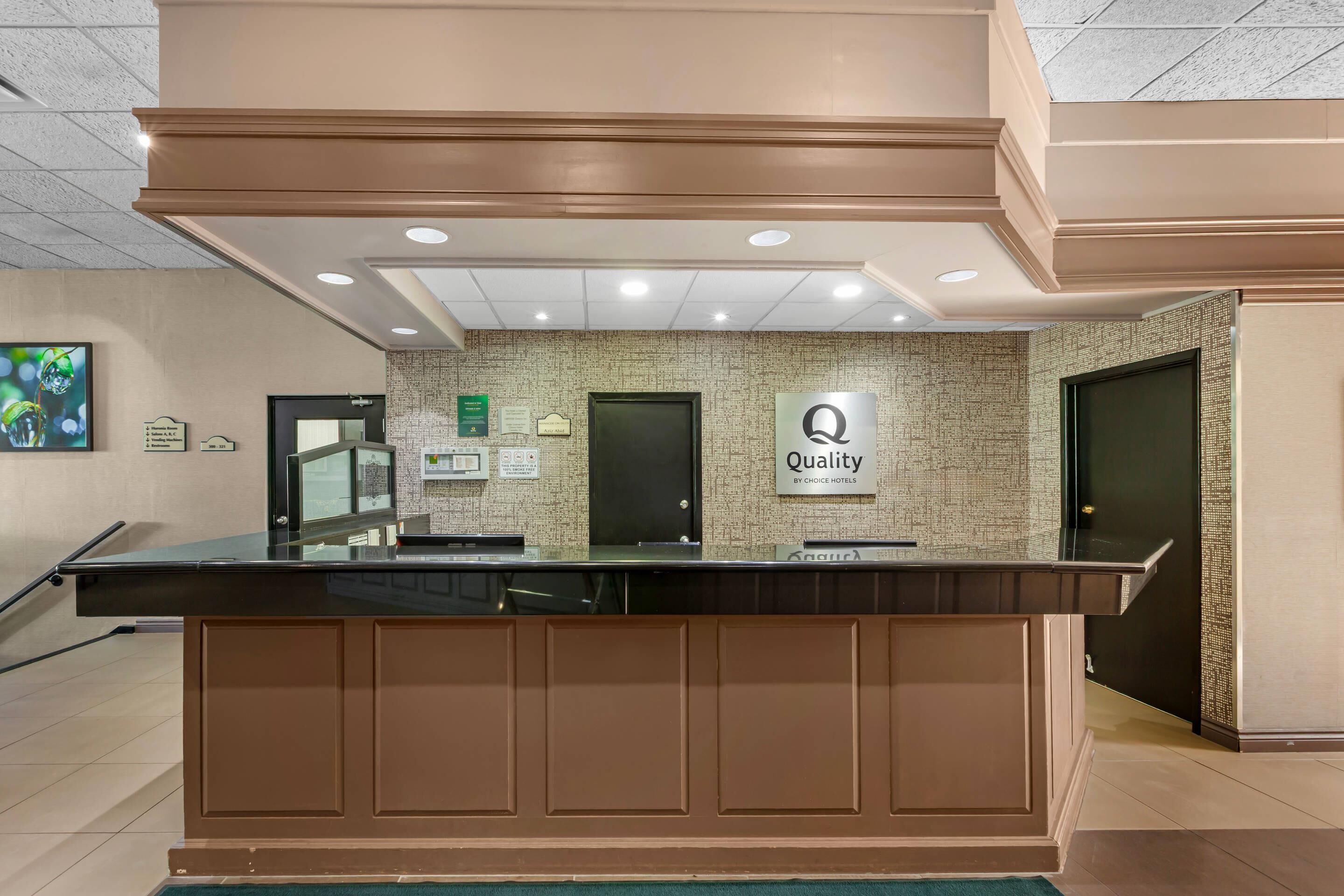A hotel reception desk with a sign indicating 'Quality by Choice Hotels.'