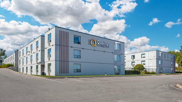 A multi-story Quality Inn hotel with a modern design, featuring a prominent logo on the facade.