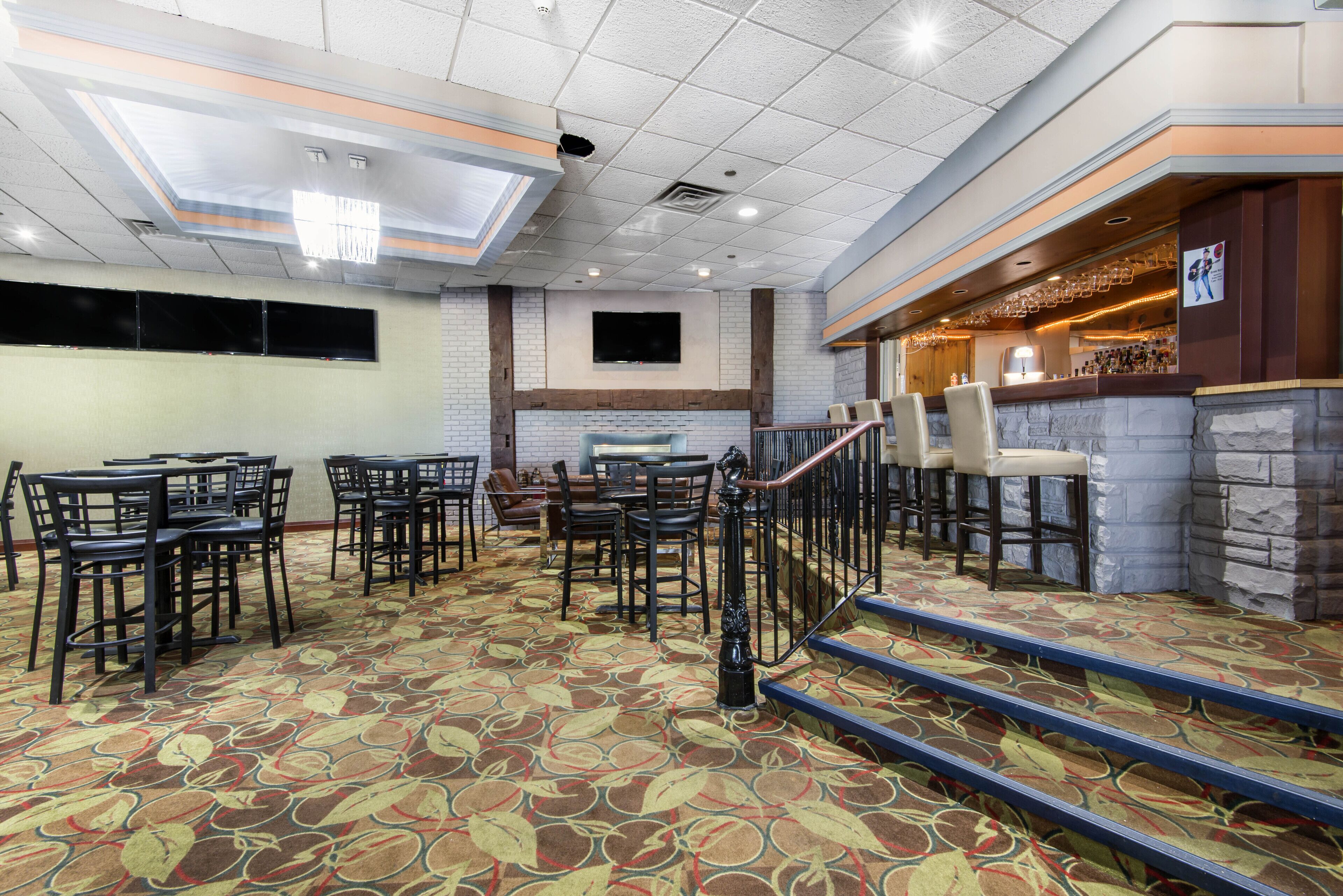 A hotel lobby with a patterned carpet, a bar area, and multiple seating arrangements.
