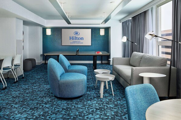 Un moderno vestíbulo de hotel con alfombra azul, zona de estar y un mostrador de recepción.