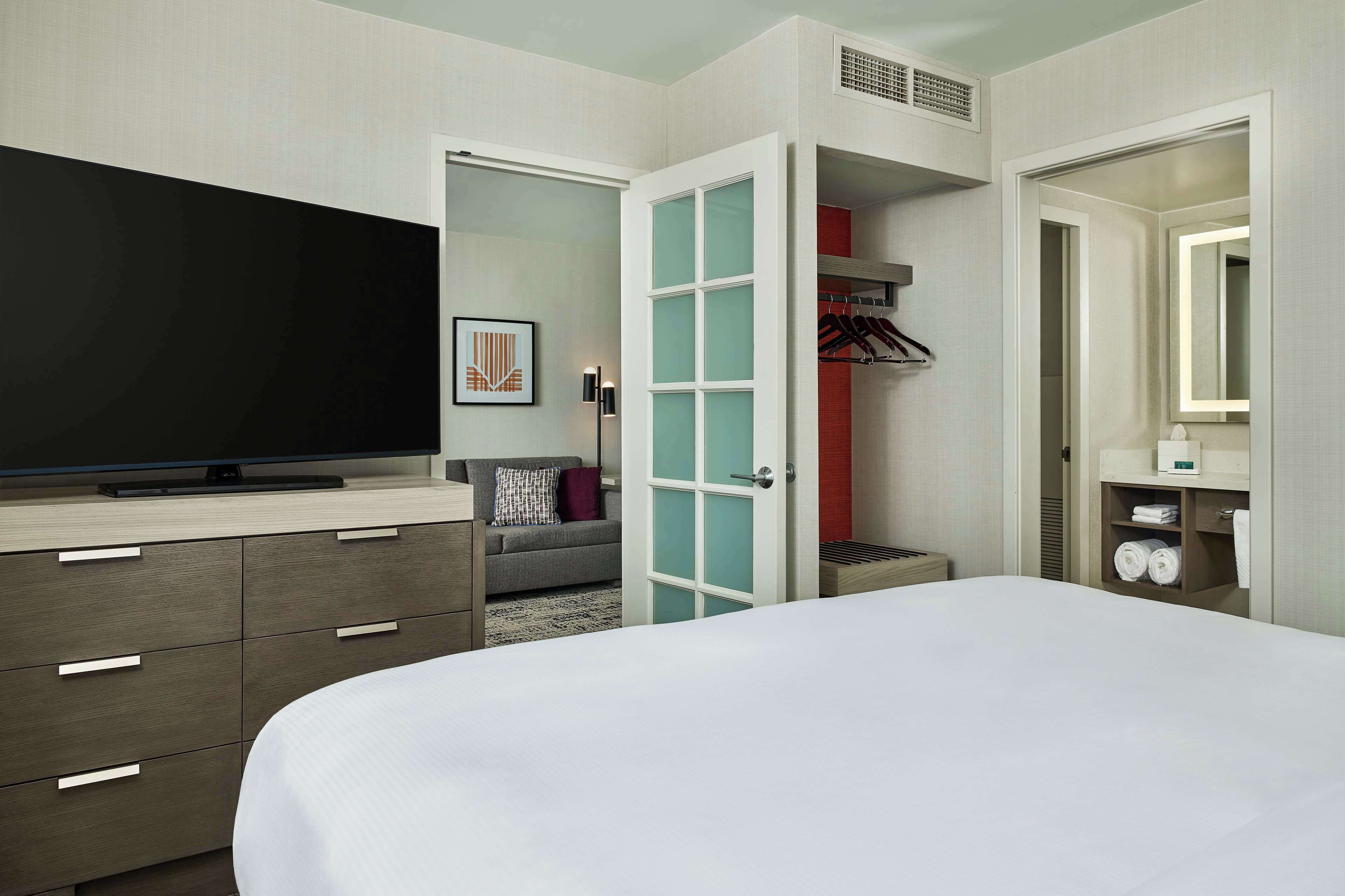 A hotel room with a bed, a television, a wardrobe, and a mirror.