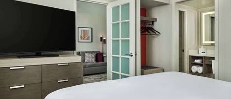 A hotel room with a bed, a television, a wardrobe, and a mirror.