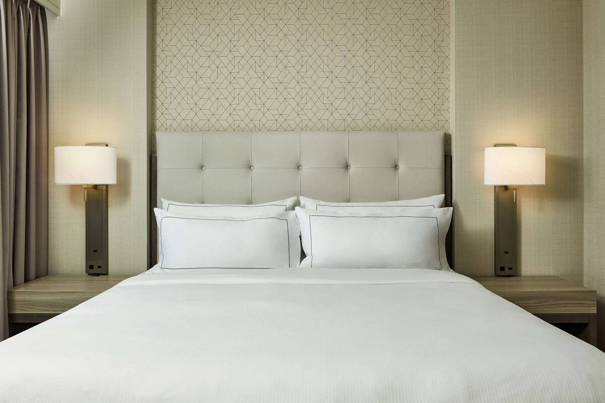 Ein Hotelzimmer mit einem großen Bett, zwei Nachttischen und zwei Wandlampen.