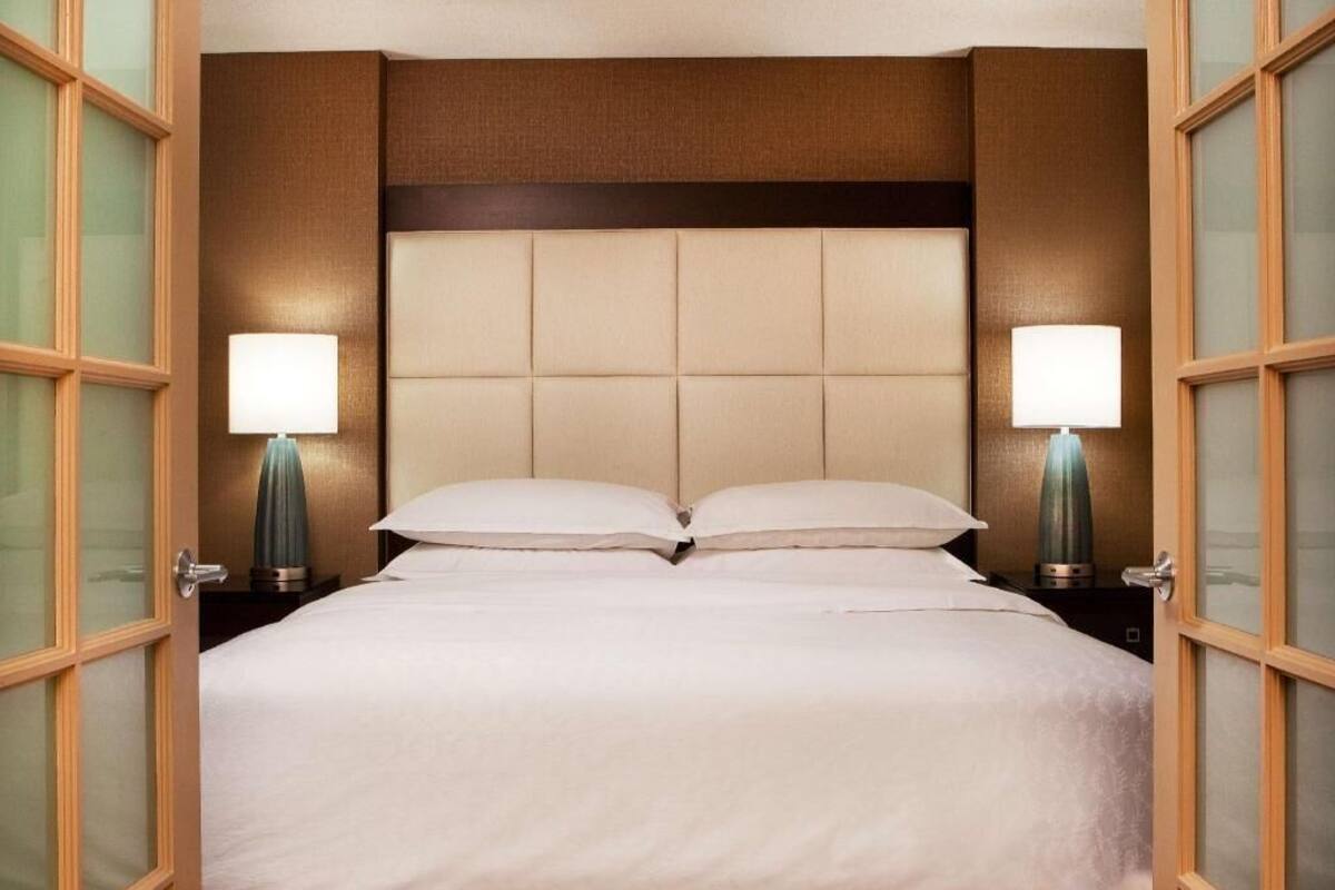 Ein Hotelzimmer mit einem großen Bett, zwei Nachttischlampen und einem Holzkopfstück.