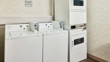 A laundry area with two Whirlpool washers and a stacked dryer unit.
