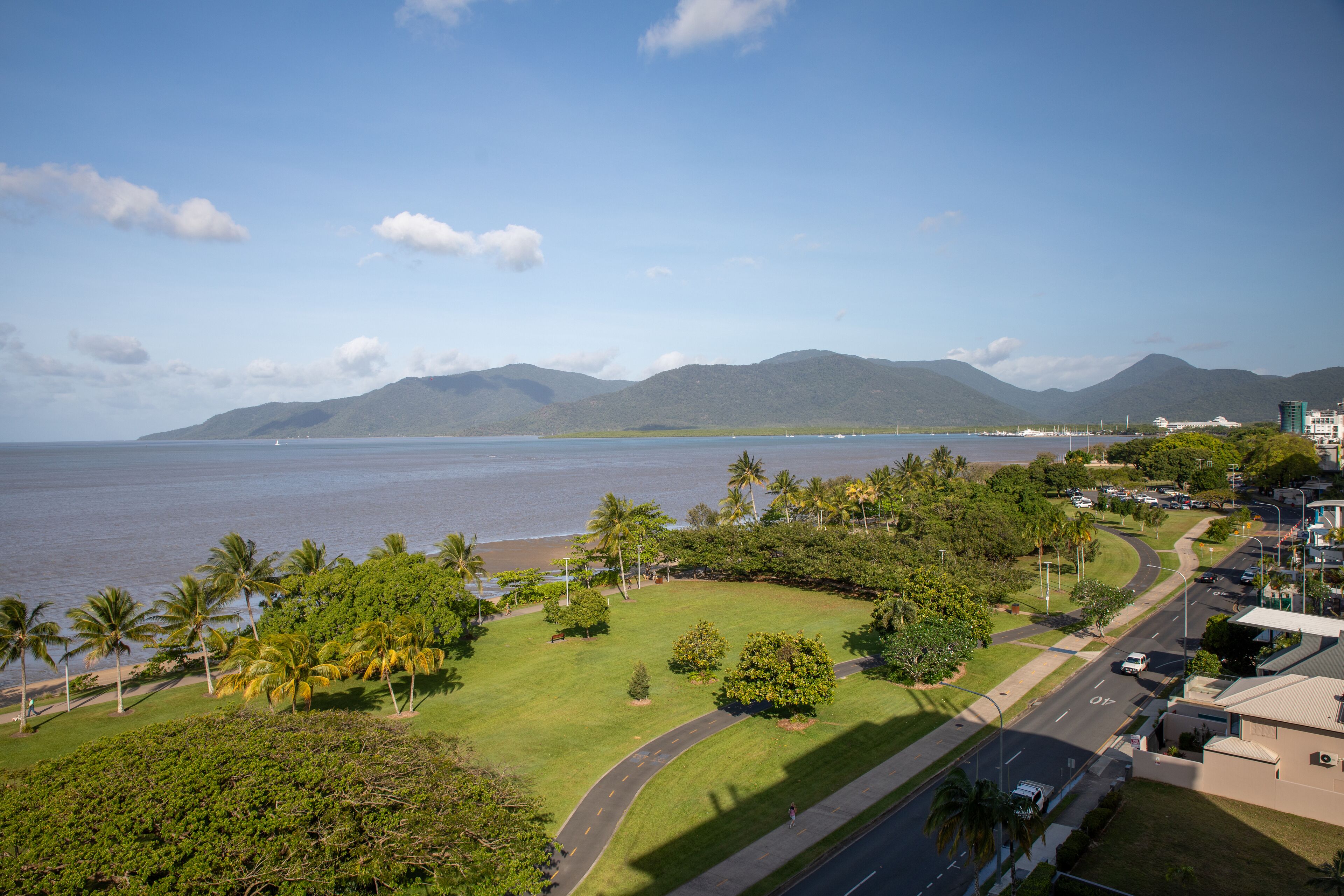 A coastal view with a road, greenery, and buildings.
