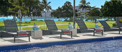 Un espace aménagé au bord de la piscine, avec des chaises longues et une vue sur l’océan.