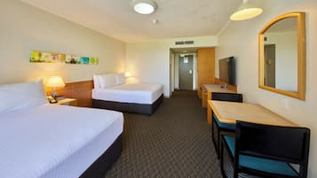 Une chambre d’hôtel avec deux lits, un bureau avec une chaise, une télévision et un miroir.