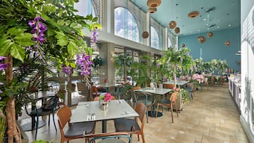 An indoor restaurant with tables, chairs, and hanging baskets of flowers.