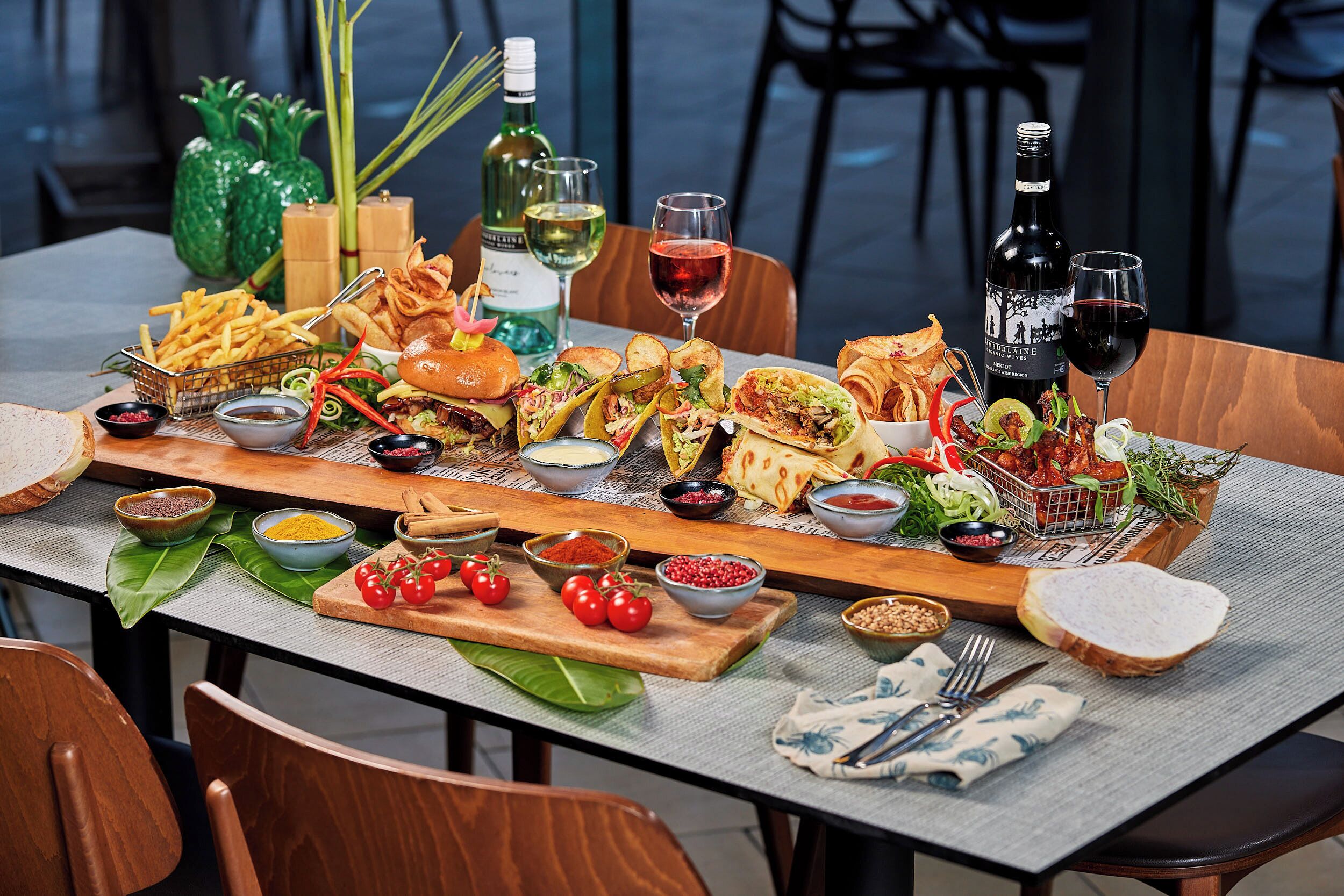Une table dressée avec différents plats, boissons et condiments, ce qui laisse présager un repas agréable.