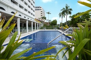 Relax by the pool surrounded by lush greenery and the hotel's modern architecture.
