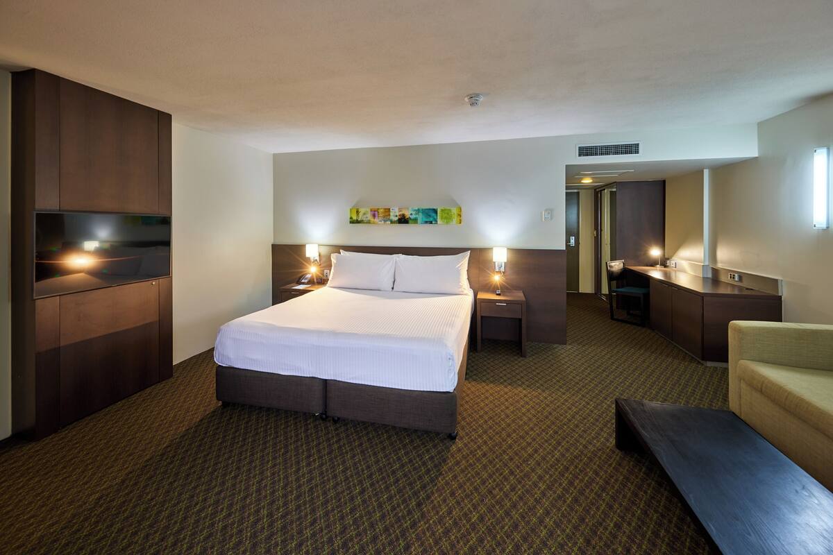 Habitación de hotel con una cama grande, un escritorio, una silla y un televisor.
