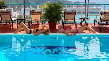 A poolside area with lounge chairs and a potted plant.