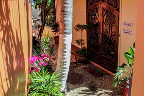 A courtyard with a decorative iron gate, potted plants, and a stone floor. - Mafolie Hotel (St. Thomas)