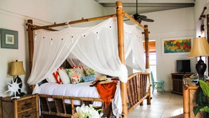 A room with a four-poster bed, a television, a lamp, and a painting on the wall.