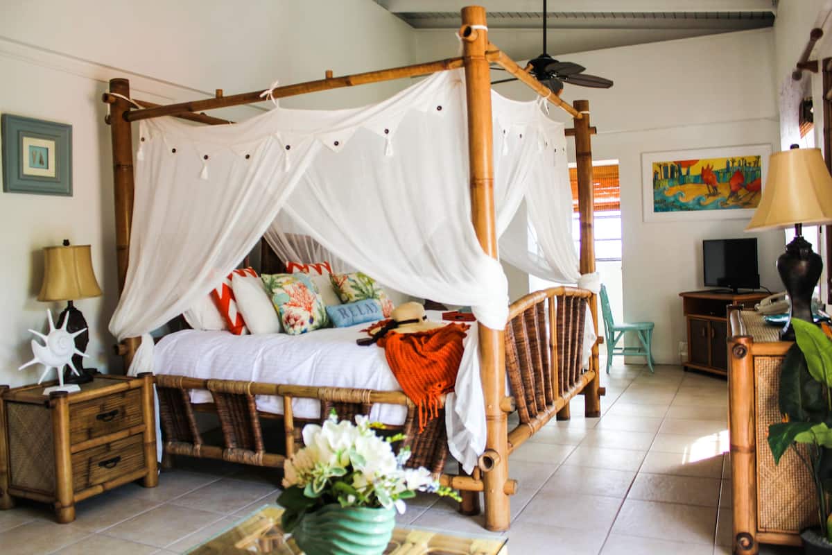 A room with a four-poster bed, a television, a lamp, and a painting on the wall.