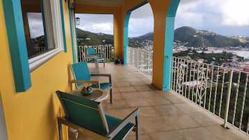 Un balcon avec des chaises et une table, d’où l’on a vue sur la ville et les collines.