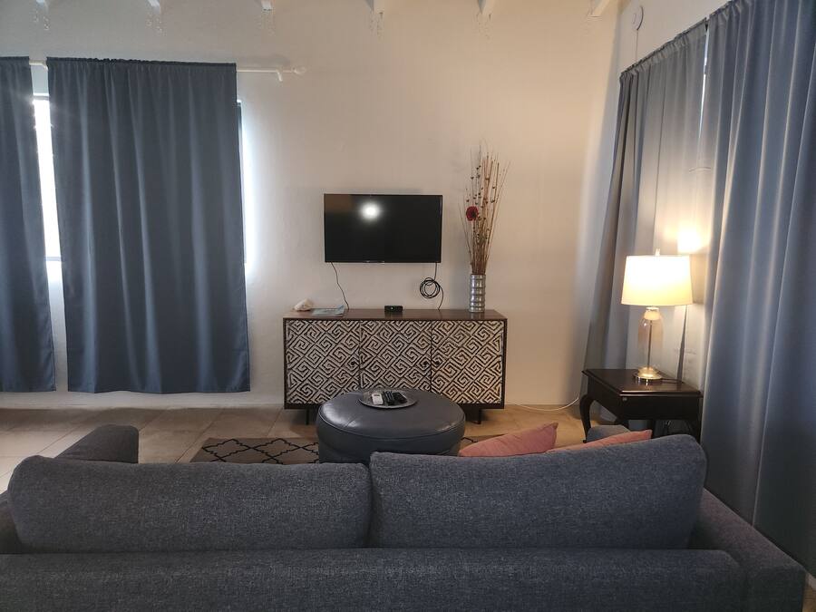 A modern living room with a grey sofa, a patterned cabinet, a flat-screen TV, and a vase with dried branches.