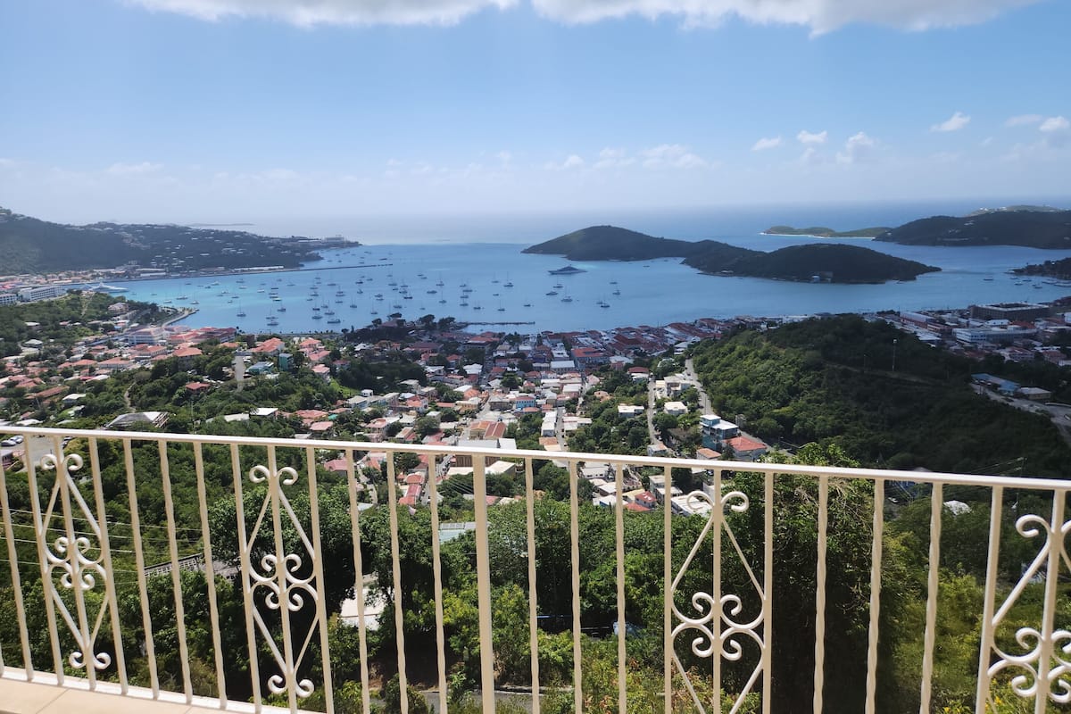 A coastal town with a marina, surrounded by hills and dense greenery.