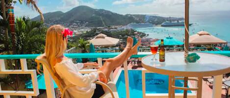 A person relaxing by a pool with a view of the sea and mountains.