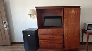 A room with a wooden cabinet containing a television, a small black refrigerator, and a white microwave on a wooden table. - Albuquerque Inn Near Airport I 40 (Albuquerque)