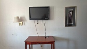A room with a TV mounted on the wall, a lamp, and a framed picture. - Albuquerque Inn Near Airport I 40 (Albuquerque)