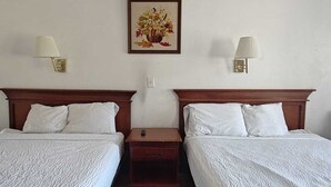 A hotel room with two beds, a nightstand, a lamp, and a framed picture on the wall. - Albuquerque Inn Near Airport I 40 (Albuquerque)