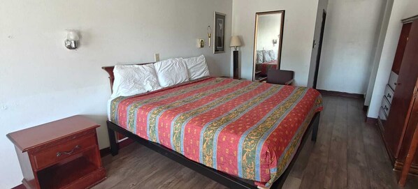 A bedroom with a bed, a nightstand, a mirror, and a wardrobe.