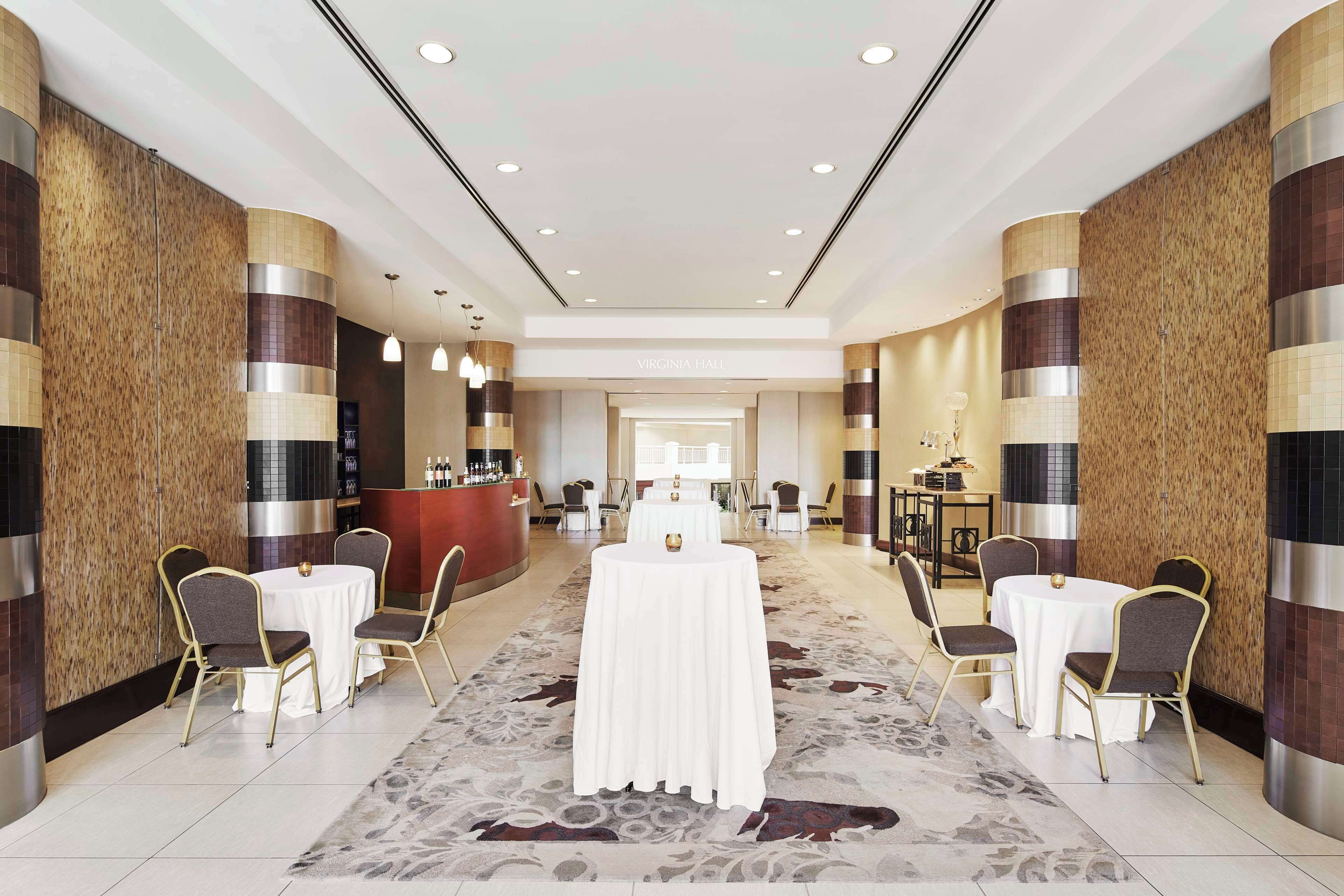 Eine Hotelhalle mit einer Rezeption, einem langen Tisch mit Stühlen und einem gemusterten Teppich.
