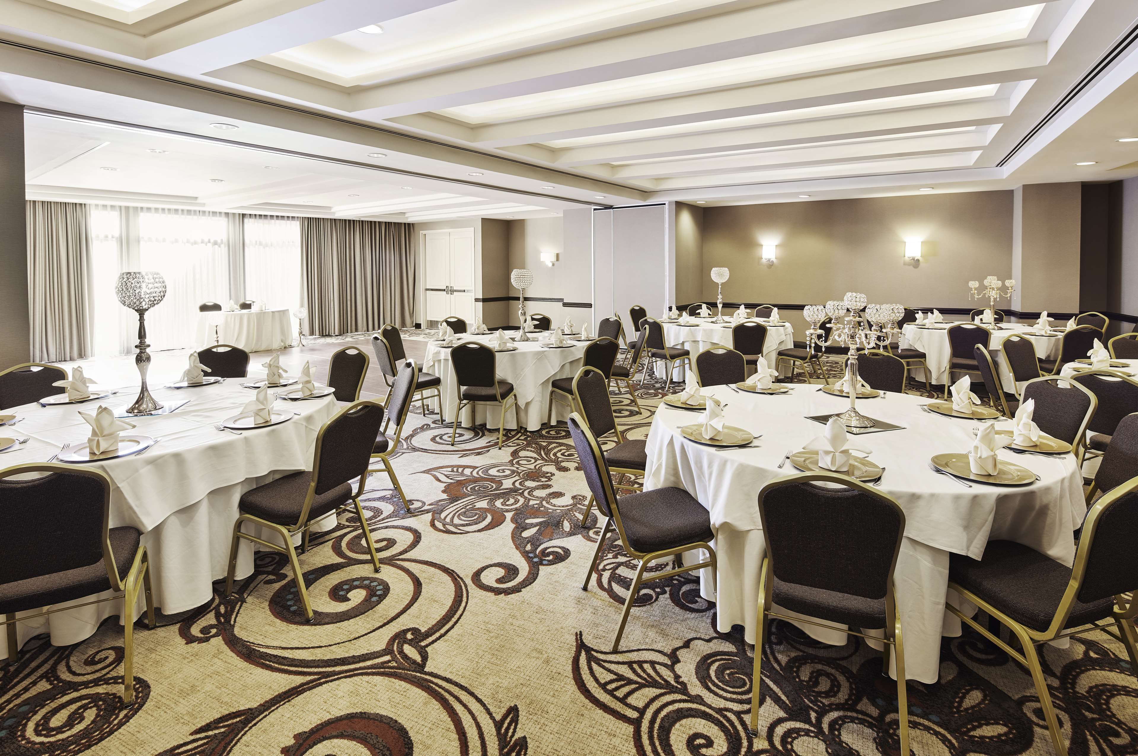 A conference room with round tables, chairs, and a carpeted floor.