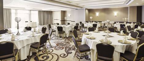 A conference room with round tables, chairs, and a carpeted floor.