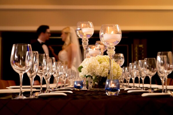 A formal dining table set with multiple wine glasses, plates, and blue candle holders. - Embassy Suites by Hilton Alexandria Old Town (Alexandria)